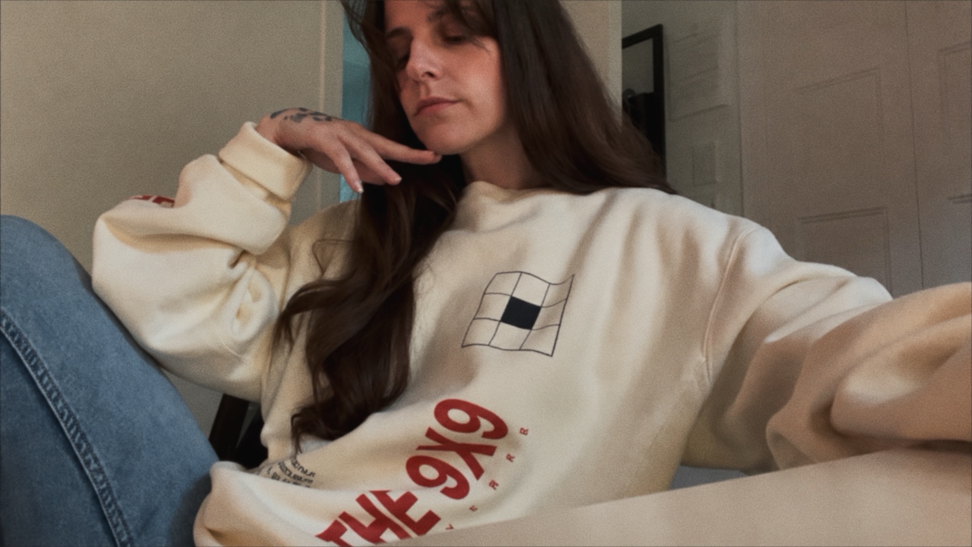 Vae Bataille wearing a cream 9X9 Universe sweatshirt.