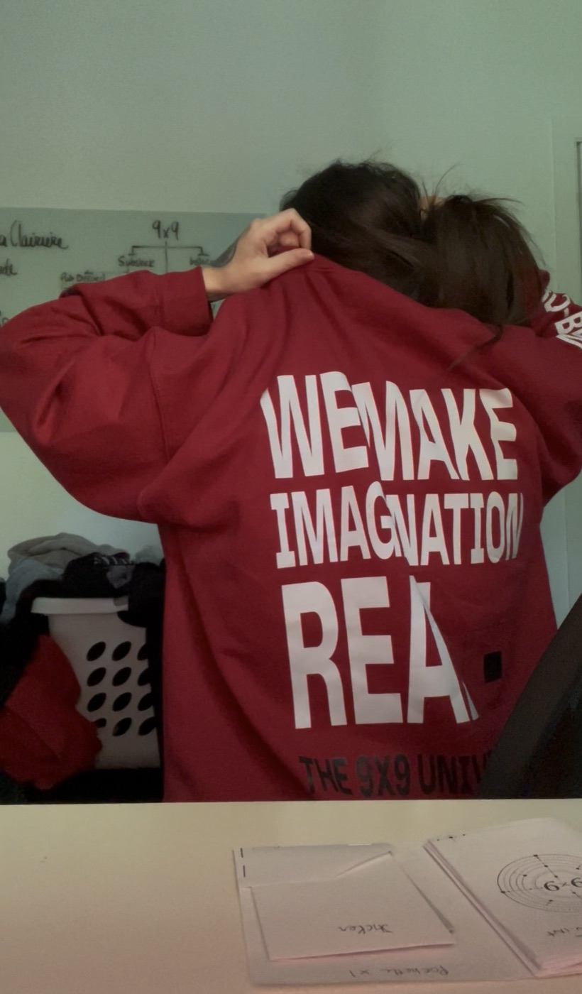 A red 9x9 Universe hoodie reading We Make Imagination Real.